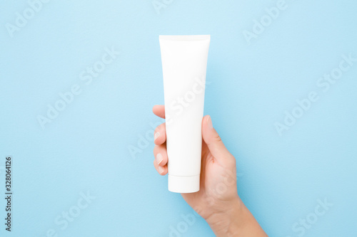 Young woman hand holding and showing white tube on light blue background Tableau sur Toile