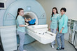 © AS Photo Family - Three female doctors near magnetic resonance imaging machine with patient inside.