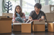 © Pormezz - Concept young couple moving house. Asian young couple make high five hands after finish packing cardboard box prepare for relocation apartment.