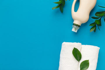 Washing detergent in bioplastic bottle with green leaves on blue