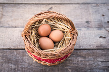 Three Chicken Eggs Lying On The Hay In Basket