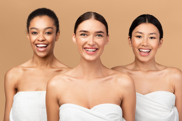 Multiracial Girls Wrapped In Bath Towels Posing Over Beige Background