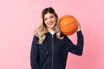 Wall Mural - Teenager girl over isolated pink background with ball of basketball