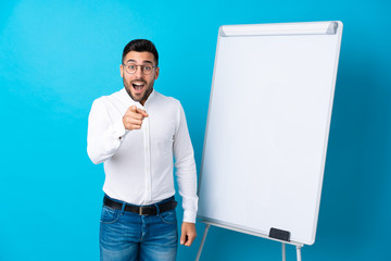 Wall Mural - Businessman giving a presentation on white board giving a presentation on white board and surprised while pointing front