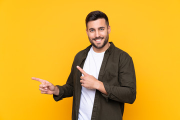 Wall Mural - Man over isolated yellow background pointing finger to the side