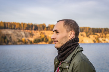 Profile of a man in a scarf snood outdoors on a lake background