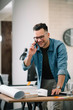 © JustLife - Businessman in office. Handsome man talking on phone at work.