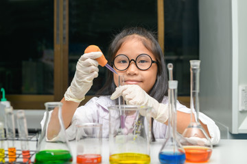 Wall Mural - happy little girl wearing lab coat making experiment