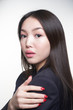 Portrait of a young beautiful Asian girl standing sideways to the camera, looking directly into the camera, wearing a blue jacket. The concept of skin care and hair
