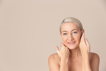 Wall Mural - Portrait of beautiful mature woman on beige background. Space for text