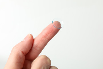 Wall Mural - Female hand holds contact lens on white background, close up