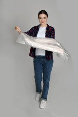 Poster - Young woman holding hanger with jacket on light grey background. Dry-cleaning service