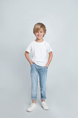 Cute little boy in casual outfit on light grey background