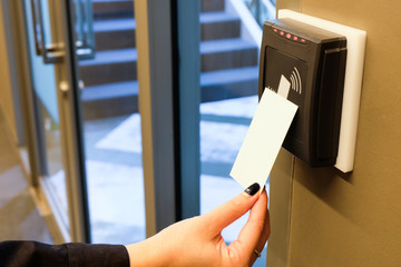 Women hand reaching to use RFID key card to access to office building area and workspace. In building security only for authorized person