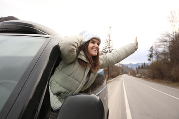 Sticker - Happy woman leaning out of car window on road. Winter vacation