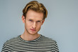 Close up studio portrait of young handsome confident blond man wearing striped t-shirt, posing against light gray background. Copy, empty space for text