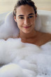 © PhotoAlto - Portrait of smiling young woman relaxing while taking a bath in bathtub