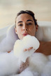 © PhotoAlto - Portrait of young woman blowing foam while taking bubble bath in bathroom