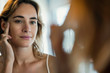 © PhotoAlto - Close-up of young woman examining her skin in bathroom mirror