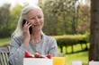 © PhotoAlto - Smiling senior woman talking on smart phone while sitting in garden
