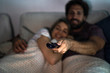 © PhotoAlto - Close-up of man operating remote control while watching television with his wife in bedroom