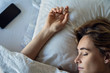 © PhotoAlto - Close-up of young woman sleeping on bed near smartphone in bedroom