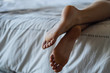 © PhotoAlto - Close-up of young woman's legs while lying on bed in bedroom