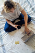 © PhotoAlto - Elevated view of young woman using laptop and smartphone on bed in bedroom
