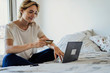 © PhotoAlto - Smiling young woman using laptop while making payment through credit card