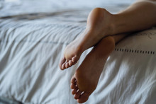 Close-up Of Young Woman's Legs While Lying On Bed In Bedroom