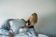 © PhotoAlto - Playful young couple having pillow fight on bed