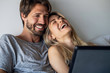 © PhotoAlto - Happy young couple watching movie on digital tablet in bedroom