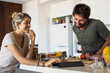 © PhotoAlto - Happy young couple using digital tablet while cooking in kitchen