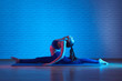 Flexible plastic girl doing pilates exercises on mat in yoga studio, body stretching pose
