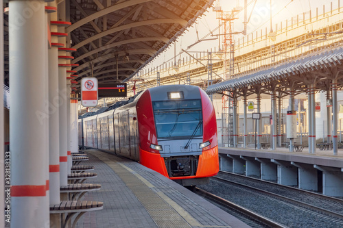 Fotografía Passenger electric subway train arrives at a platform with benches for people