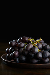 Dark purple grape on wooden plate. Vintage wooden table, high resolution