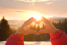 Woman Making Heart With Hands Outdoors At Sunset, Closeup. Winter Vacation