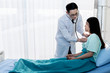 © Anatta_Tan - Asian male doctor Using a stethoscope Lisen to heart rate Of female patients, which lying on the patient's bed, with white background, to health care and insurance concept.