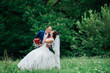 Wedding photo shoot. Bride and groom in the park each other. Newlyweds in love in a green park. Romantic, fairytale, happy newlywed couple hugging and kissing in a park, trees in background