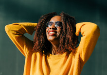 Smiling Young Woman Wearing Sunglasses Standing Outdoors In Sunlight