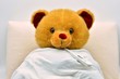 © Kuki LadrondeGuevara - Oso de peluche enfermo en la cama con el termómetro puesto