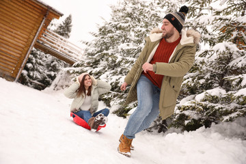 Wall Mural - Young man pulling sled with his girlfriend outdoors on snowy day. Winter vacation