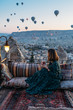 © Cavan Images - Woman drinking early morning tea with hot air balloons in Cappadocia