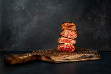 Wall Mural - four grilled steaks with spices on a stone background. Four types of meat frying Rare, Medium, Medium Well, Well Done