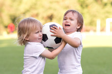 Two Little Toddlers Arguing At Football Field Or Playground Over Soccer Ball Trying To Take Or Grab Ball. Conflict Management, Corporate Fight Metaphor And Conflict Resolving Concept