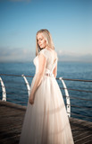 Fototapeta Na drzwi - happy bride in a wedding dress,wedding outfit bride,young duffel is spinning in a wedding dress on a background of the sea,morning wedding photo shoot of the bride,bride portrait