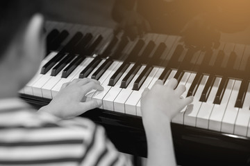 Selective focus to kid fingers and  piano key to play the piano.