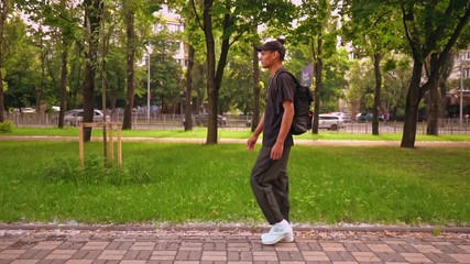 Leinwandbilder - mixed race young man in casual trendy clothes and backpack walking on the street in urban city slow motion