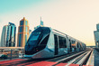 Metro train on rail line in Dubai downtown with skyscrapers at background, copy space