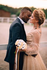 Wall Mural - An African man and a Caucasian woman romantically touch each other in the sunset light. Close-up portrait.